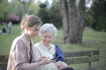 Young woman teaches older woman how to use smartphone.