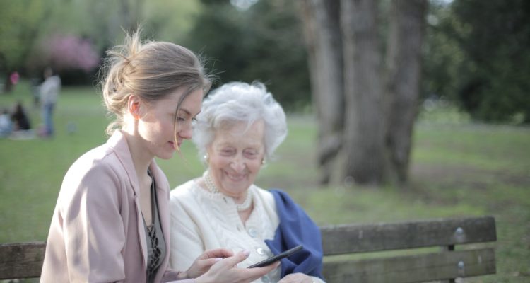 Young woman teaches older woman how to use smartphone.